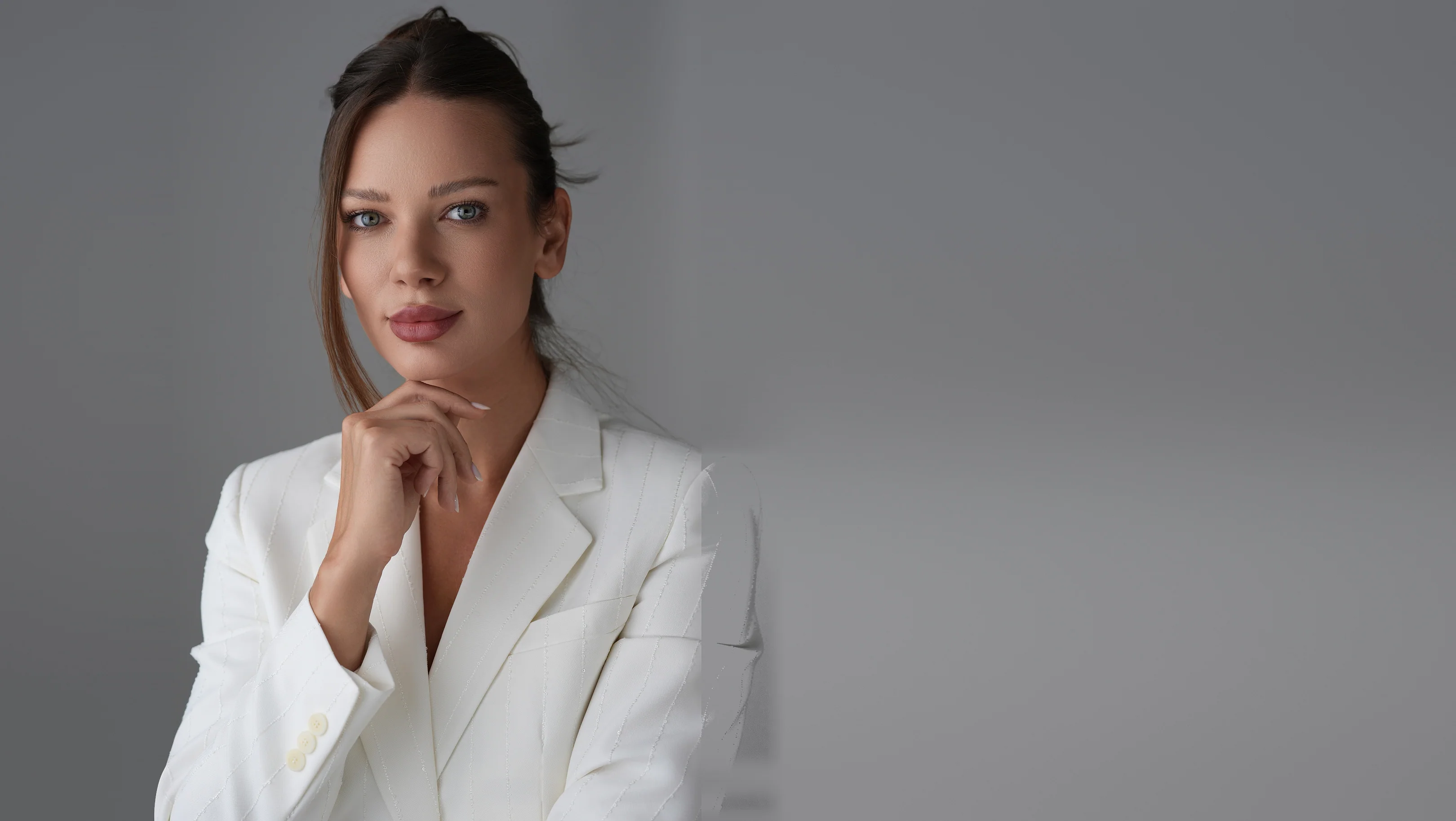 Roxana Diaconu in a white blazer, her hand at her chin.